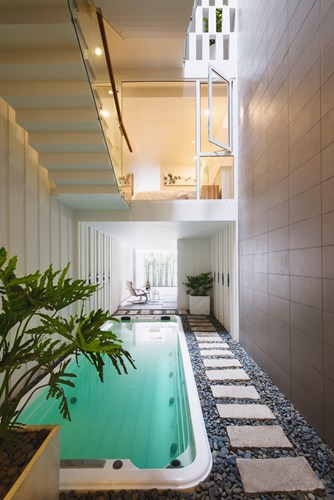 ''
Tầng 1 được bố trí bể bơi và cây xanh khiến không gian ngôi nhà trở nên dịu mát.
''